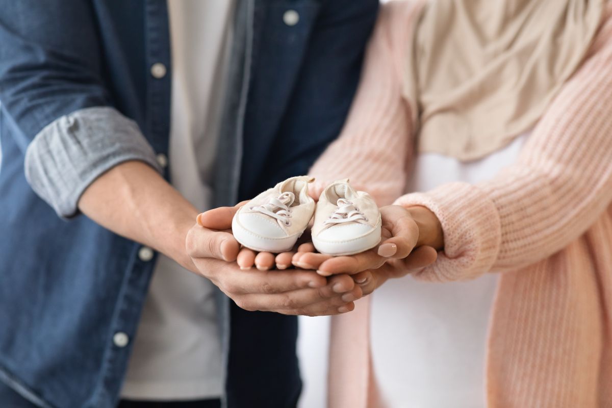 happy-couple-hold-baby-shoes-in-their-hands pregnancy announcement.jpg